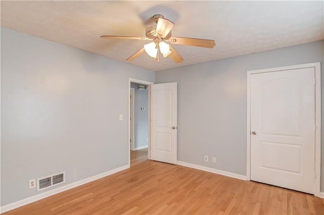 empty room with light wood finished floors, baseboards, visible vents, and ceiling fan