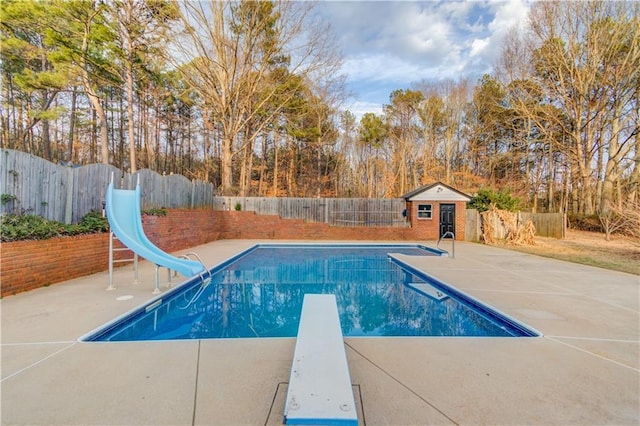 view of pool featuring an outbuilding, a water slide, a fenced backyard, a diving board, and a fenced in pool