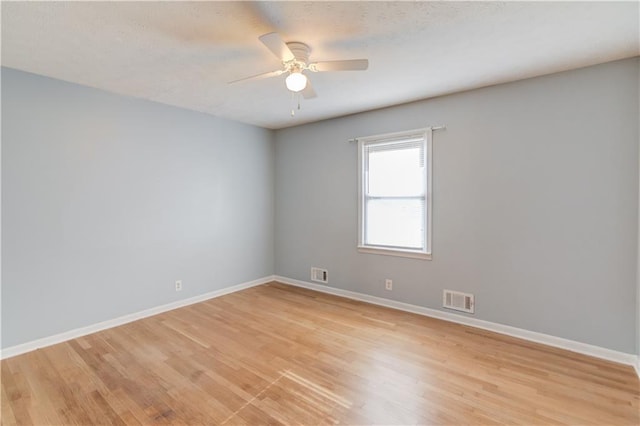 empty room featuring baseboards, visible vents, and light wood finished floors