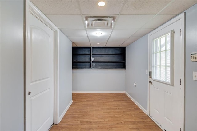 doorway with baseboards, a paneled ceiling, visible vents, and light wood-style floors