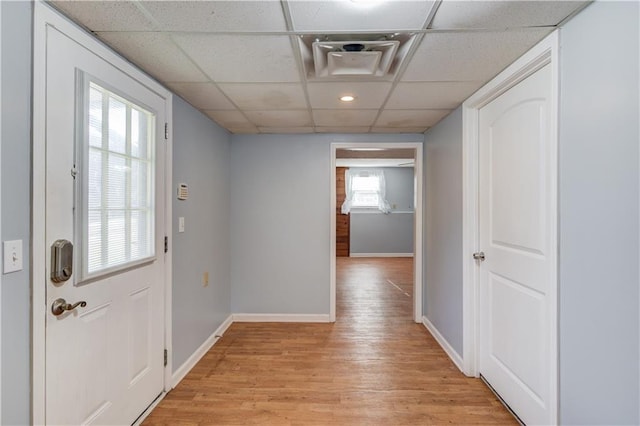 doorway to outside with a paneled ceiling, light wood-style flooring, and baseboards