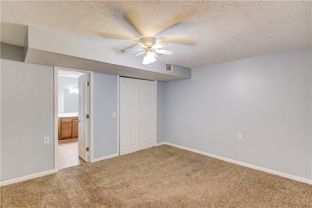 unfurnished bedroom with a textured ceiling, light carpet, and baseboards