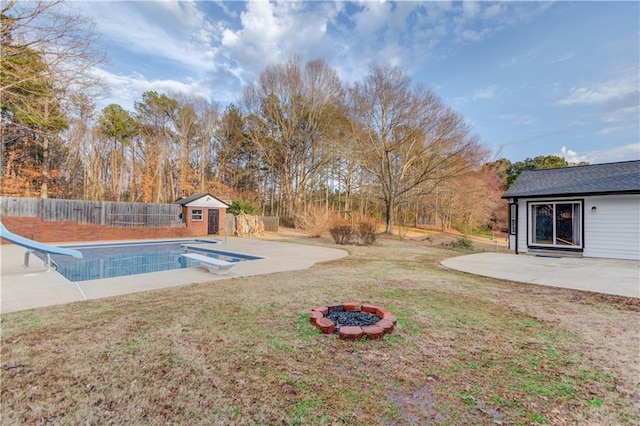 view of swimming pool with an outbuilding, a patio area, a water slide, a fenced backyard, and a diving board