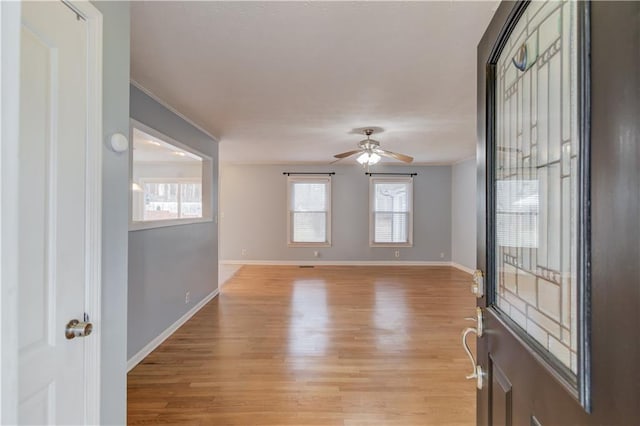 foyer entrance featuring baseboards, ornamental molding, a ceiling fan, and light wood-style floors