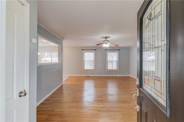 spare room with light wood-style floors, crown molding, and baseboards