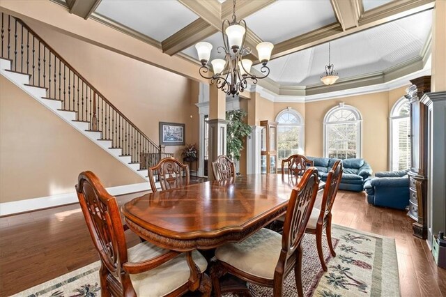 dining space with ornate columns, ornamental molding, coffered ceiling, dark wood-type flooring, and a chandelier