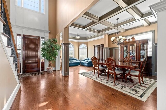 dining room featuring an inviting chandelier, coffered ceiling, hardwood / wood-style flooring, ornamental molding, and beamed ceiling