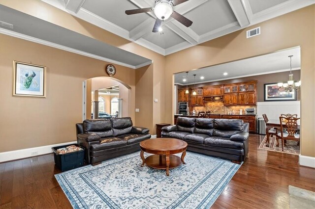 living room with beam ceiling, crown molding, dark wood-type flooring, and ceiling fan with notable chandelier