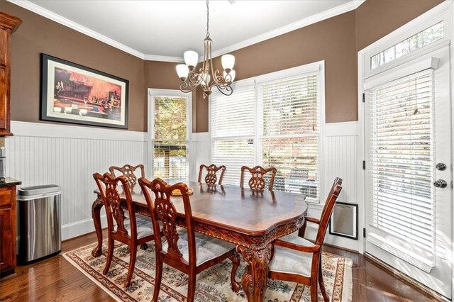 dining space featuring dark hardwood / wood-style floors, ornamental molding, and a notable chandelier