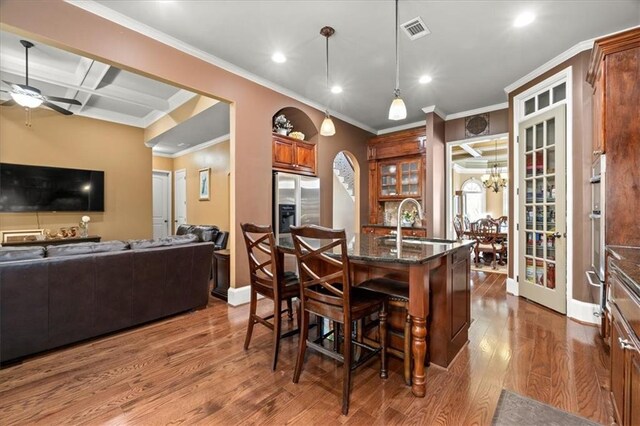 interior space featuring dark stone counters, coffered ceiling, hanging light fixtures, hardwood / wood-style flooring, and stainless steel fridge with ice dispenser