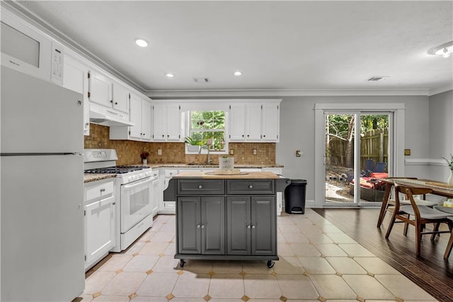 kitchen featuring light hardwood / wood-style floors, white cabinets, a center island, and white appliances