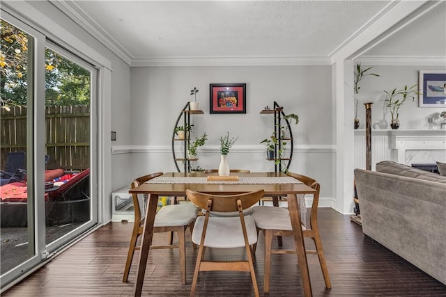 dining area featuring a textured ceiling, ornamental molding, dark hardwood / wood-style flooring, and a fireplace