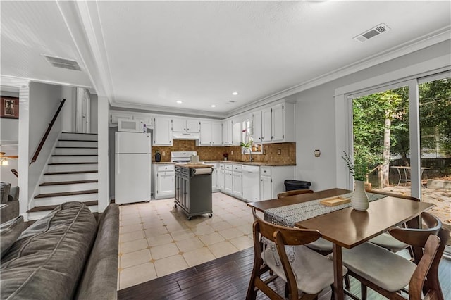 kitchen with backsplash, crown molding, white cabinets, and white appliances