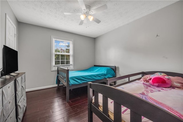 bedroom with ceiling fan, a textured ceiling, and dark hardwood / wood-style flooring