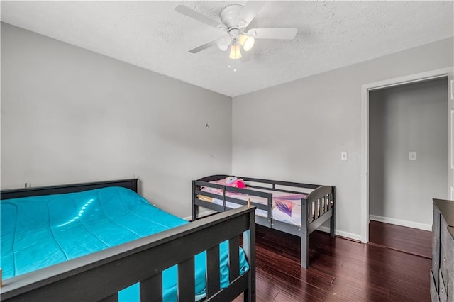 bedroom featuring a textured ceiling, dark wood-type flooring, and ceiling fan