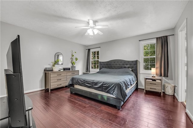 bedroom with ceiling fan, a textured ceiling, multiple windows, and dark hardwood / wood-style floors