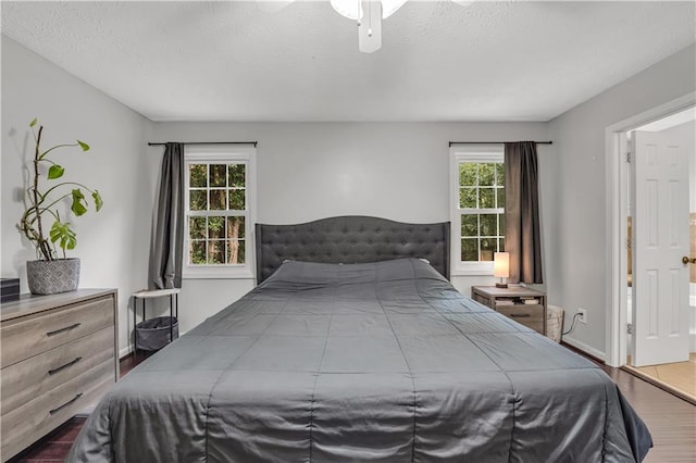 bedroom featuring multiple windows, a textured ceiling, wood-type flooring, and ceiling fan