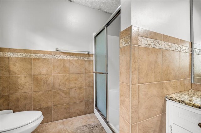 bathroom with vanity, toilet, tile walls, and an enclosed shower