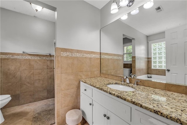 full bathroom with vanity, tile walls, shower with separate bathtub, and toilet