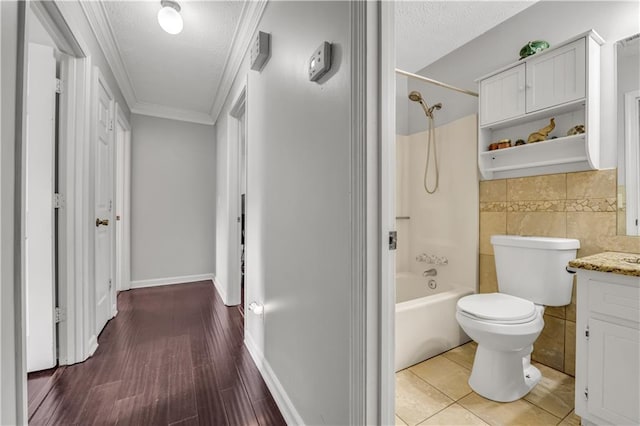 full bathroom featuring toilet, ornamental molding, hardwood / wood-style floors, vanity, and bathing tub / shower combination