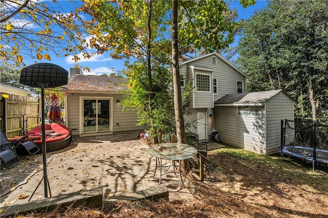 back of property featuring a patio, a storage unit, and a trampoline