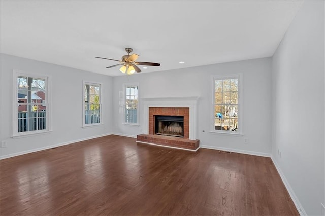 unfurnished living room with dark hardwood / wood-style flooring, a brick fireplace, and ceiling fan