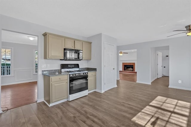 kitchen with ceiling fan, light wood-type flooring, white gas range oven, and cream cabinets