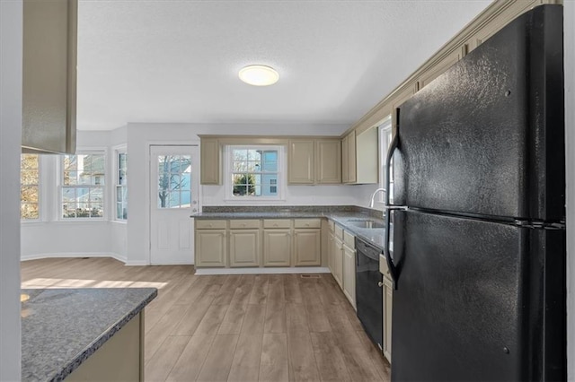 kitchen featuring sink, cream cabinetry, light wood-type flooring, and black appliances