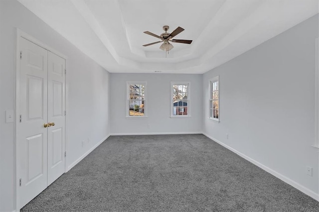 unfurnished room with carpet, a tray ceiling, and ceiling fan