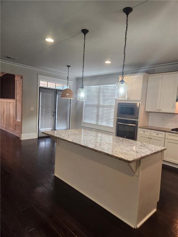 2439 Muirfield Pl, Atlanta, GA 30337 - kitchen with wall oven, stainless steel microwave, ornamental molding, dark wood-type flooring, and a center island