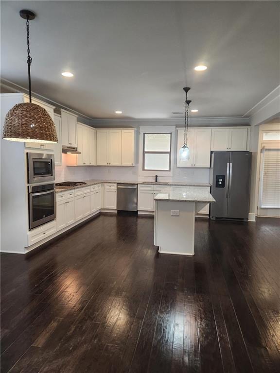 2439 Muirfield Pl, Atlanta, GA 30337 - kitchen with appliances with stainless steel finishes, under cabinet range hood, dark wood-style flooring, hanging light fixtures, and a sink