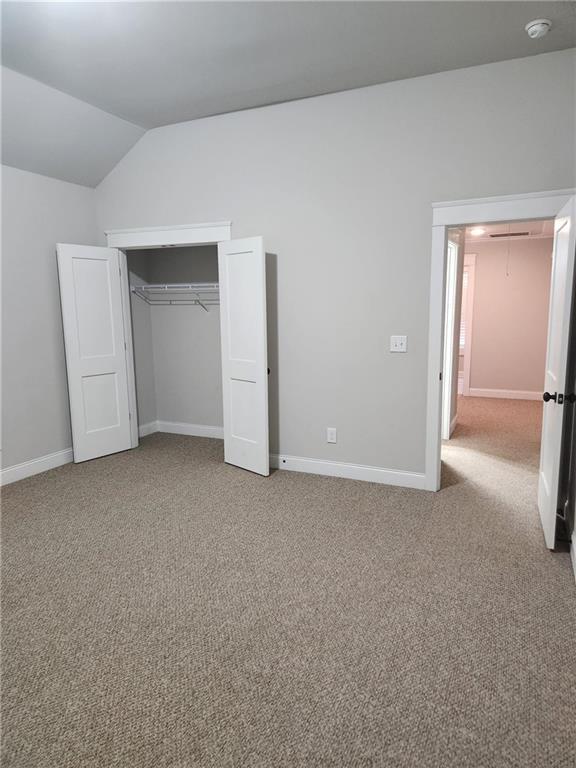 2439 Muirfield Pl, Atlanta, GA 30337 - unfurnished bedroom with lofted ceiling, carpet, baseboards, and a closet