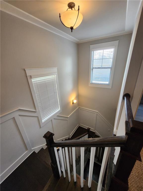 2439 Muirfield Pl, Atlanta, GA 30337 - stairs featuring wood finished floors, a decorative wall, crown molding, and wainscoting