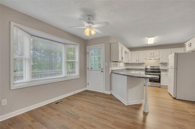 kitchen with freestanding refrigerator, light wood-style flooring, a textured ceiling, ceiling fan, and stainless steel range with gas cooktop