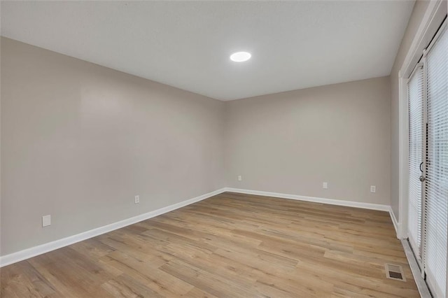 spare room featuring baseboards, visible vents, and light wood-style floors