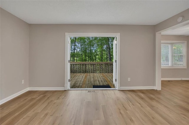 unfurnished room with wood finished floors, visible vents, and baseboards