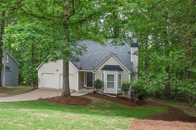 view of front of house with roof with shingles, an attached garage, a front lawn, and driveway