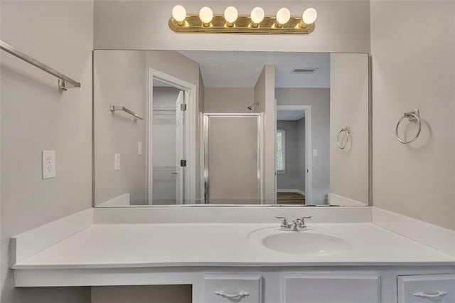 full bathroom with vanity, a shower stall, and visible vents