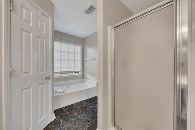 bathroom featuring a garden tub, a stall shower, a textured ceiling, visible vents, and marble finish floor