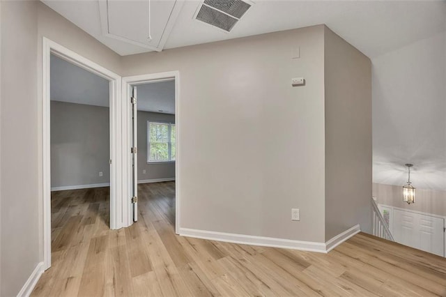 interior space featuring baseboards, light wood finished floors, attic access, and visible vents