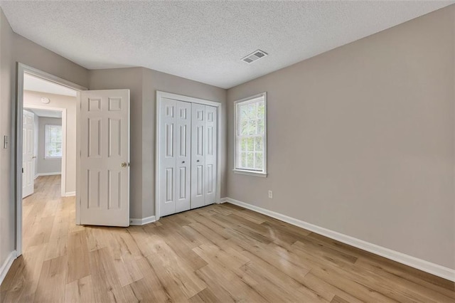 unfurnished bedroom featuring light wood-style flooring, baseboards, visible vents, and multiple windows