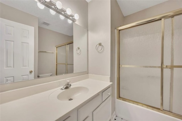 full bath with bath / shower combo with glass door, toilet, vanity, and visible vents