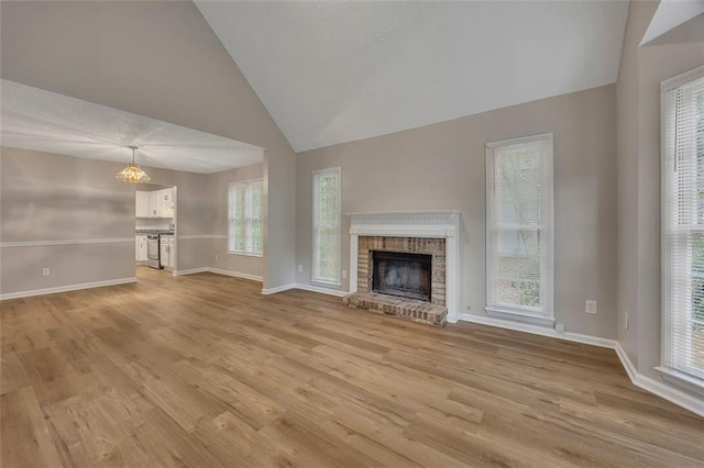unfurnished living room with vaulted ceiling, baseboards, light wood-style flooring, and a brick fireplace
