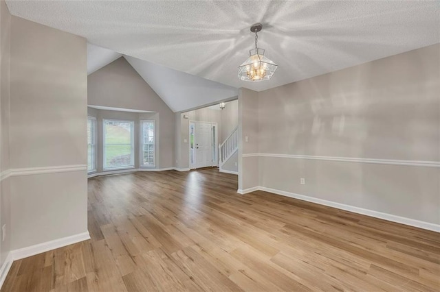 empty room featuring light wood-style floors, stairway, baseboards, and a notable chandelier