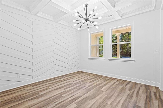 empty room with beam ceiling, crown molding, a notable chandelier, wood finished floors, and coffered ceiling