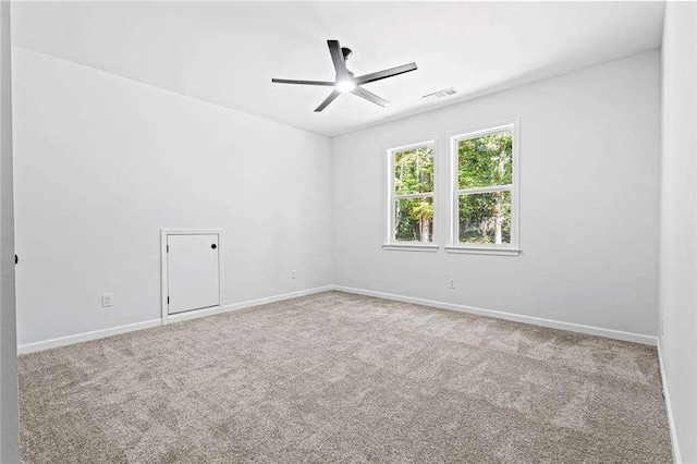 spare room featuring visible vents, carpet floors, a ceiling fan, and baseboards