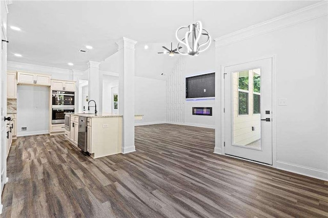 kitchen featuring decorative columns, double oven, ornamental molding, open floor plan, and a sink