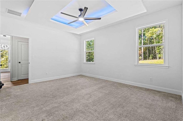 carpeted empty room with baseboards, visible vents, and a ceiling fan