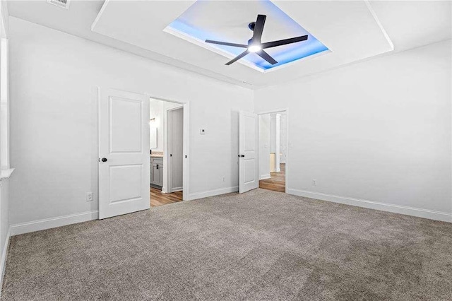 unfurnished bedroom with ensuite bath, carpet, baseboards, and a ceiling fan