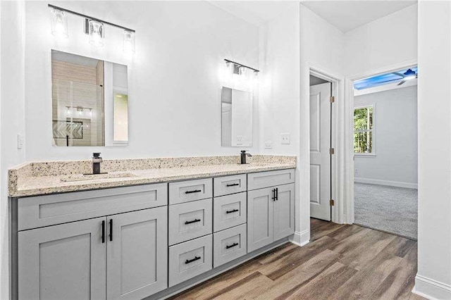 full bathroom featuring double vanity, baseboards, a sink, and wood finished floors